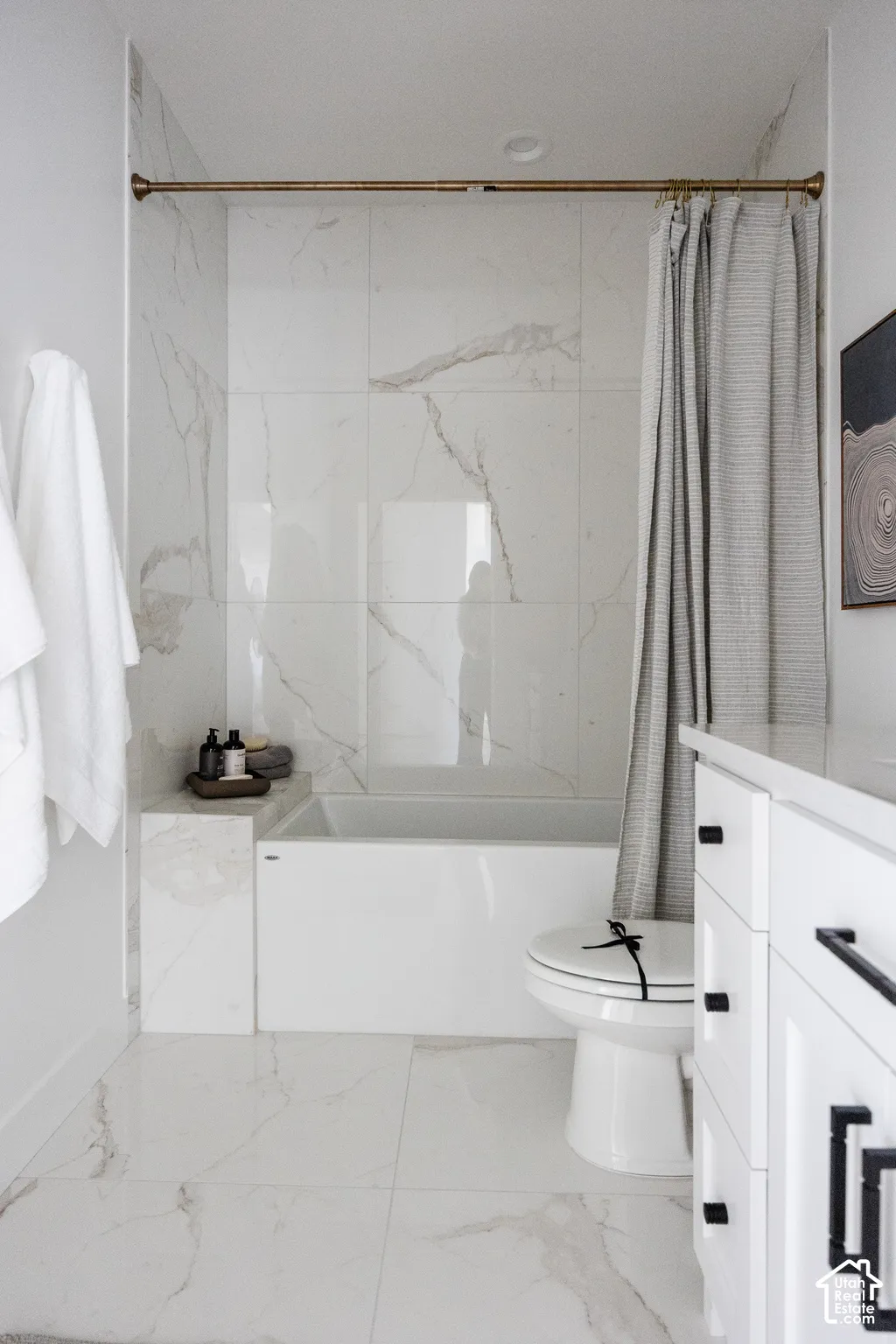 White tiled flooring, a built-in bathtub, and a toilet with a white seat