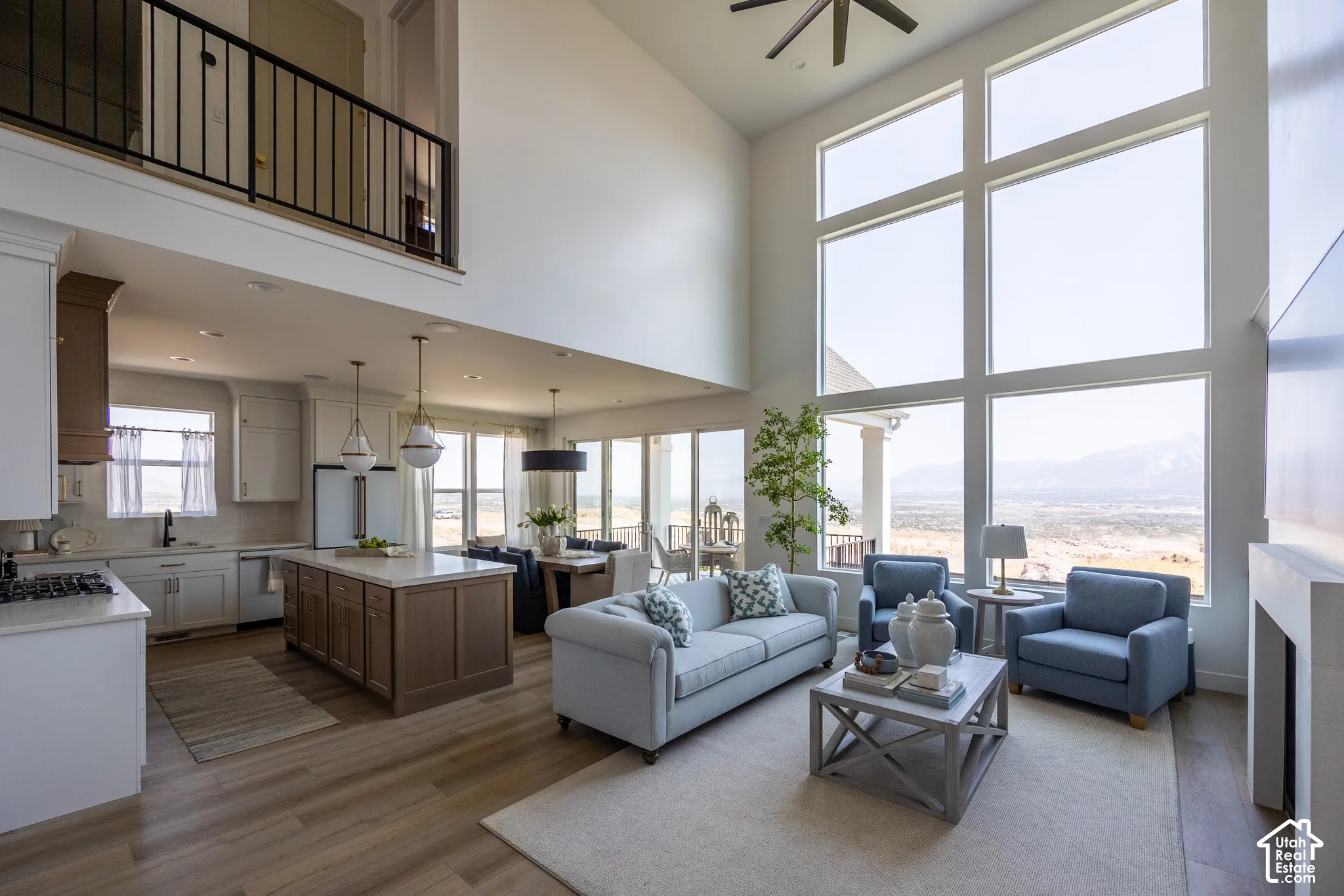 Two-story living area with expansive floor-to-ceiling windows, wood-finish flooring, and a stone-clad fireplace