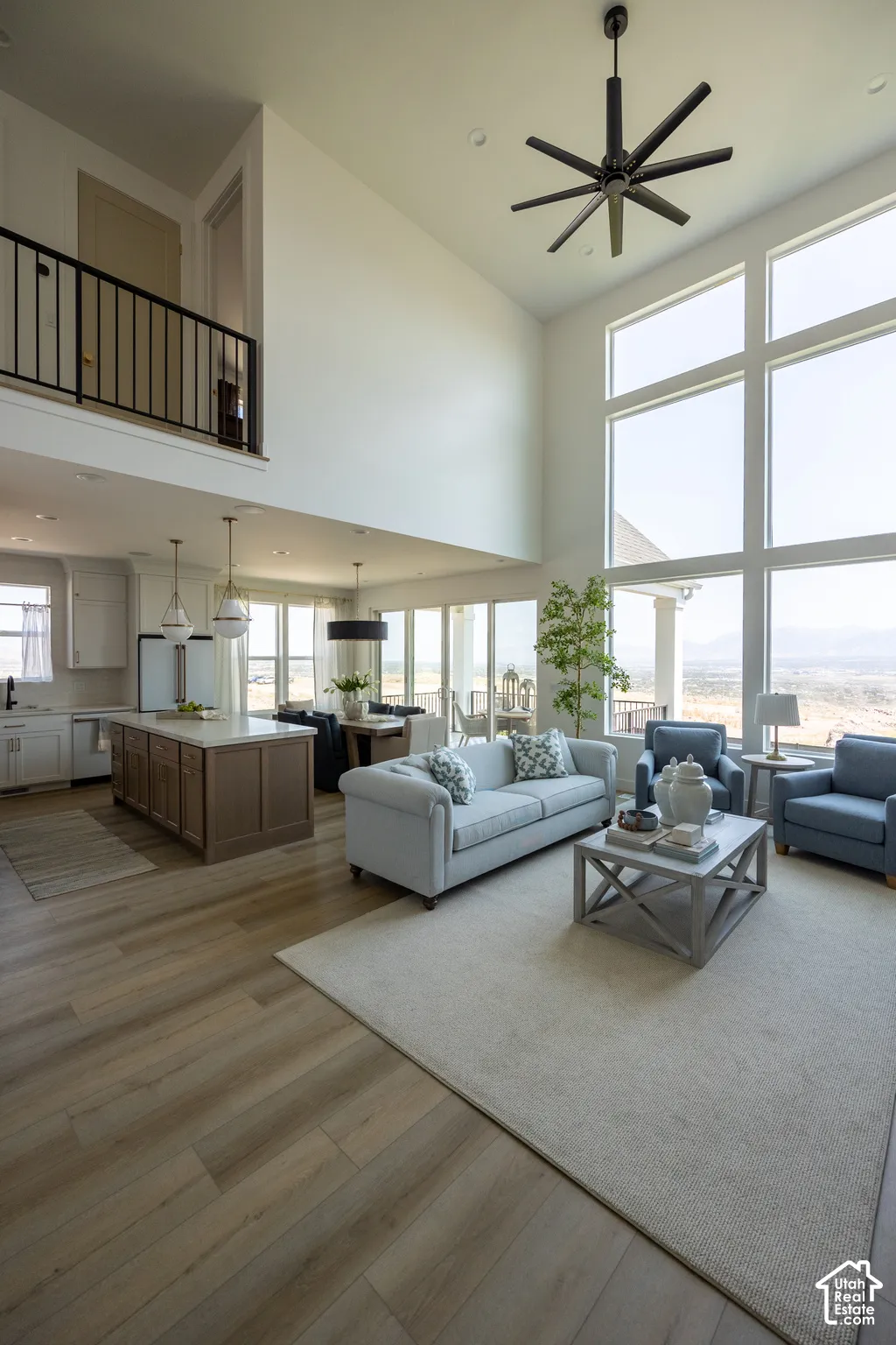 Vaulted ceilings, expansive windows, wood-finish flooring, kitchen island with built-in storage, and open-concept design