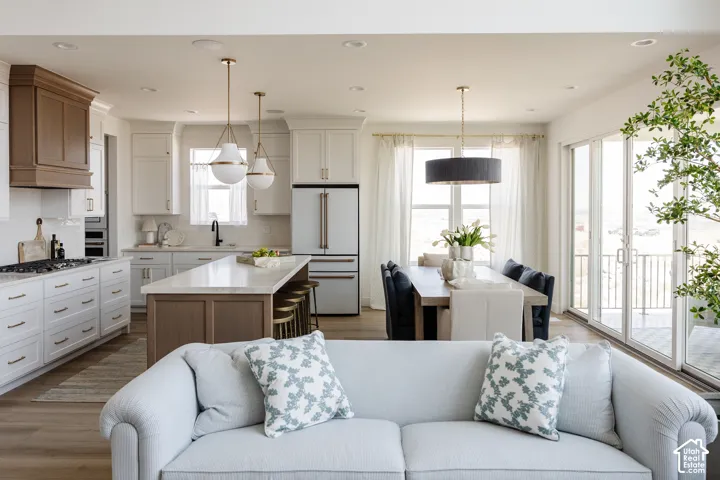 Open concept living area featuring wood-finish flooring, a kitchen island with seating, a dining area with expansive glass doors, and recessed lighting