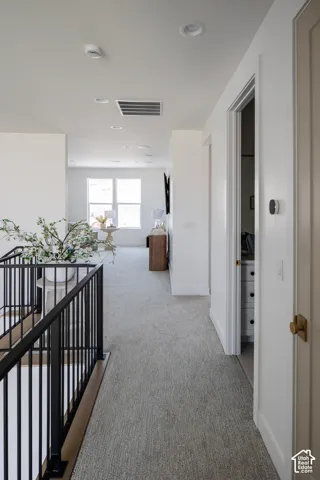 Upper-level hallway with light-toned carpeting and recessed lighting