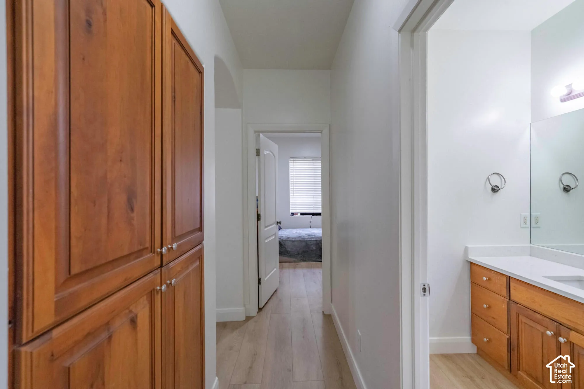 Built-in wooden cabinetry, wood-finish flooring, white walls, and a vanity with a white countertop