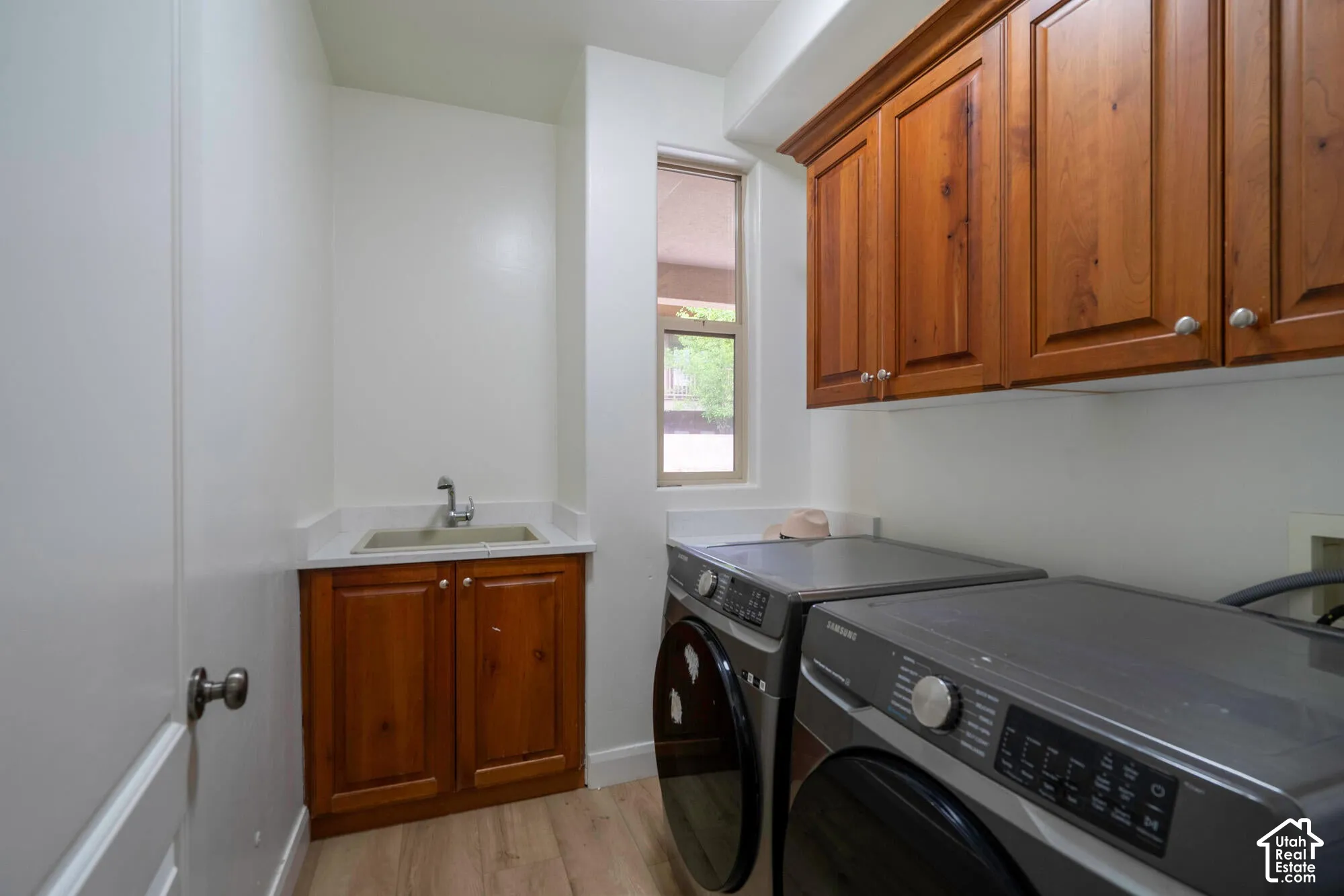 Wood-finish flooring, wood cabinetry, and a utility sink with white countertop