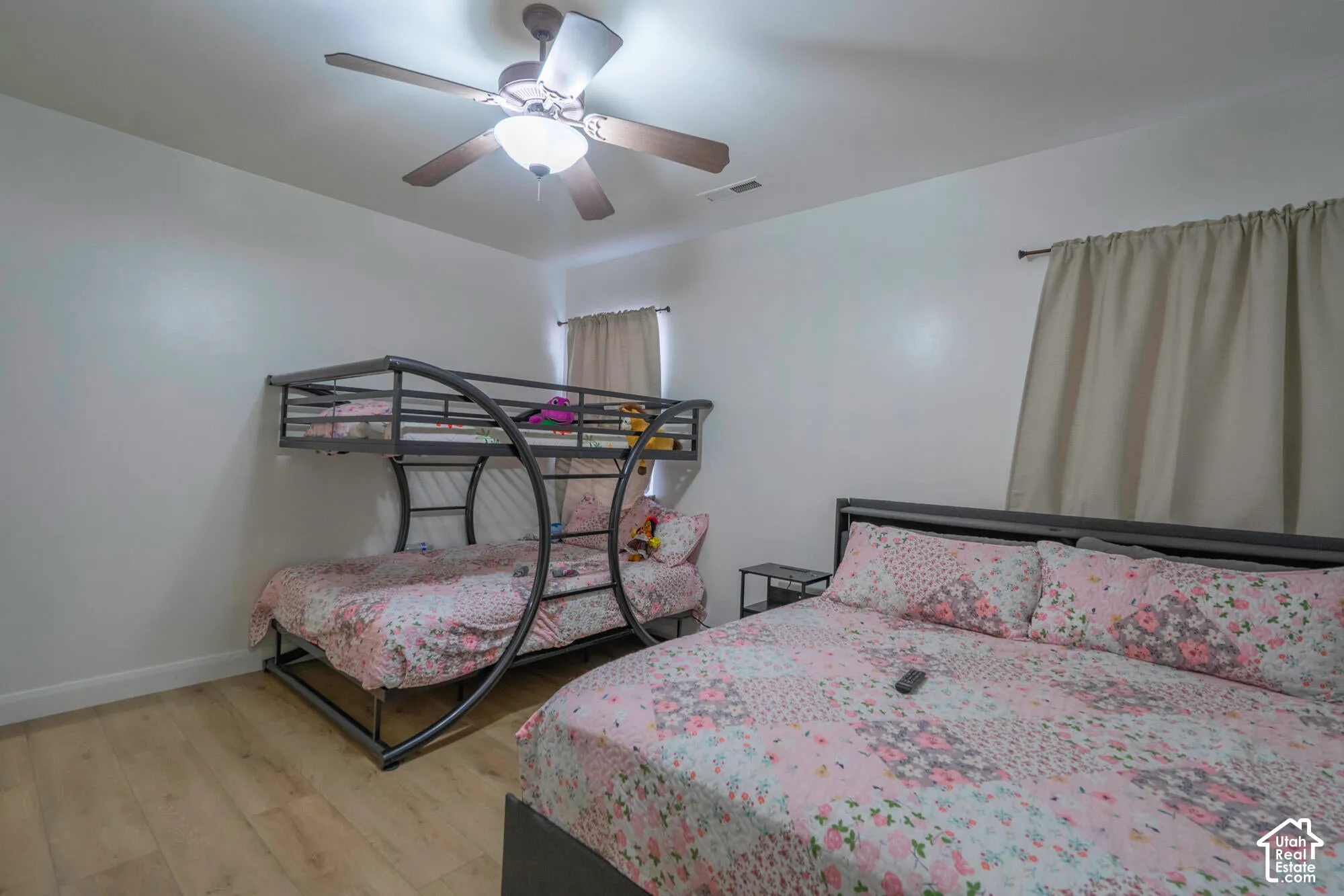 Wood-finish flooring, ceiling fan with integrated lighting, and window treatments