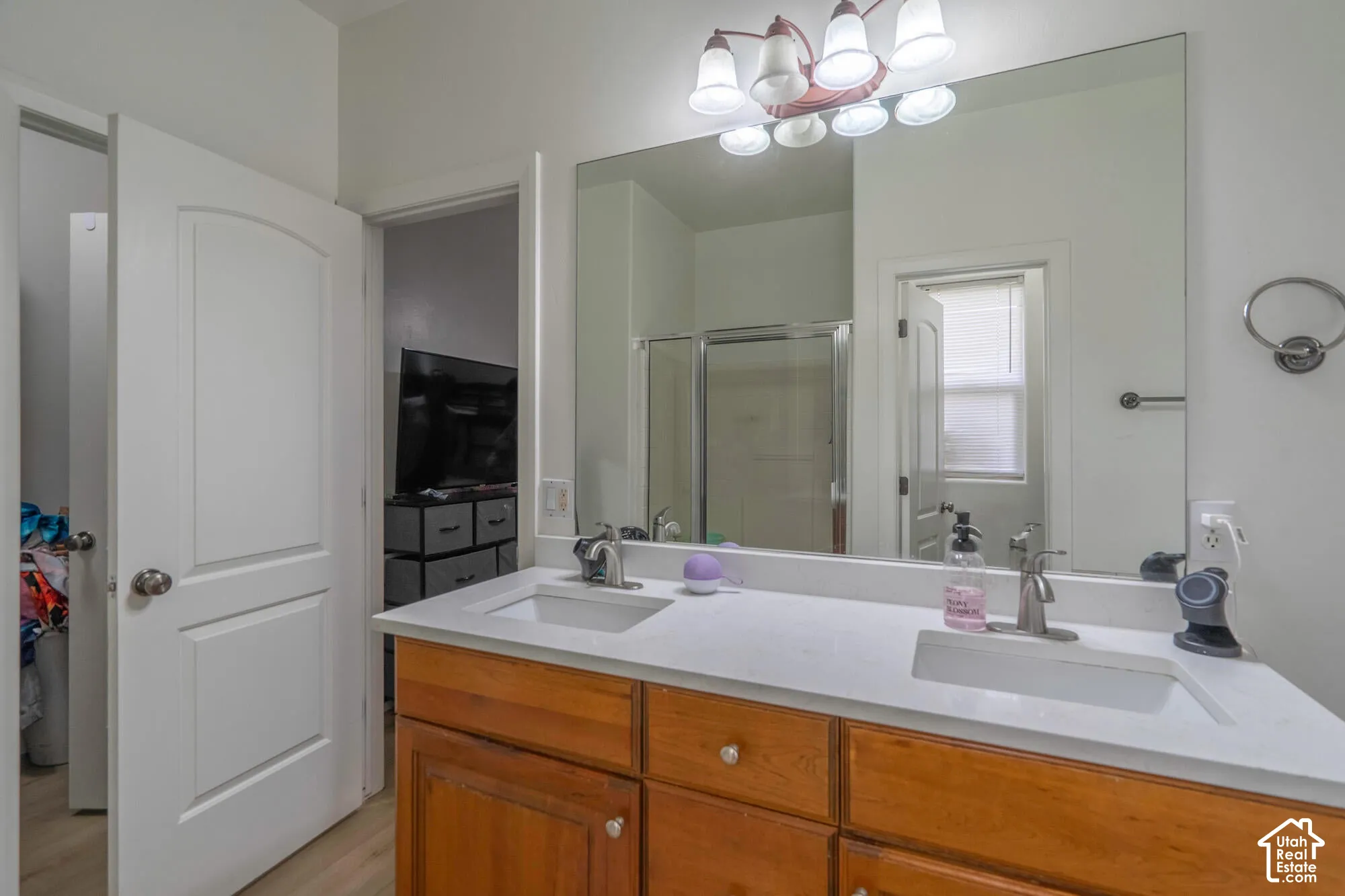 Double vanity with undermount sinks, wood-finish cabinetry, and a large wall-mounted mirror