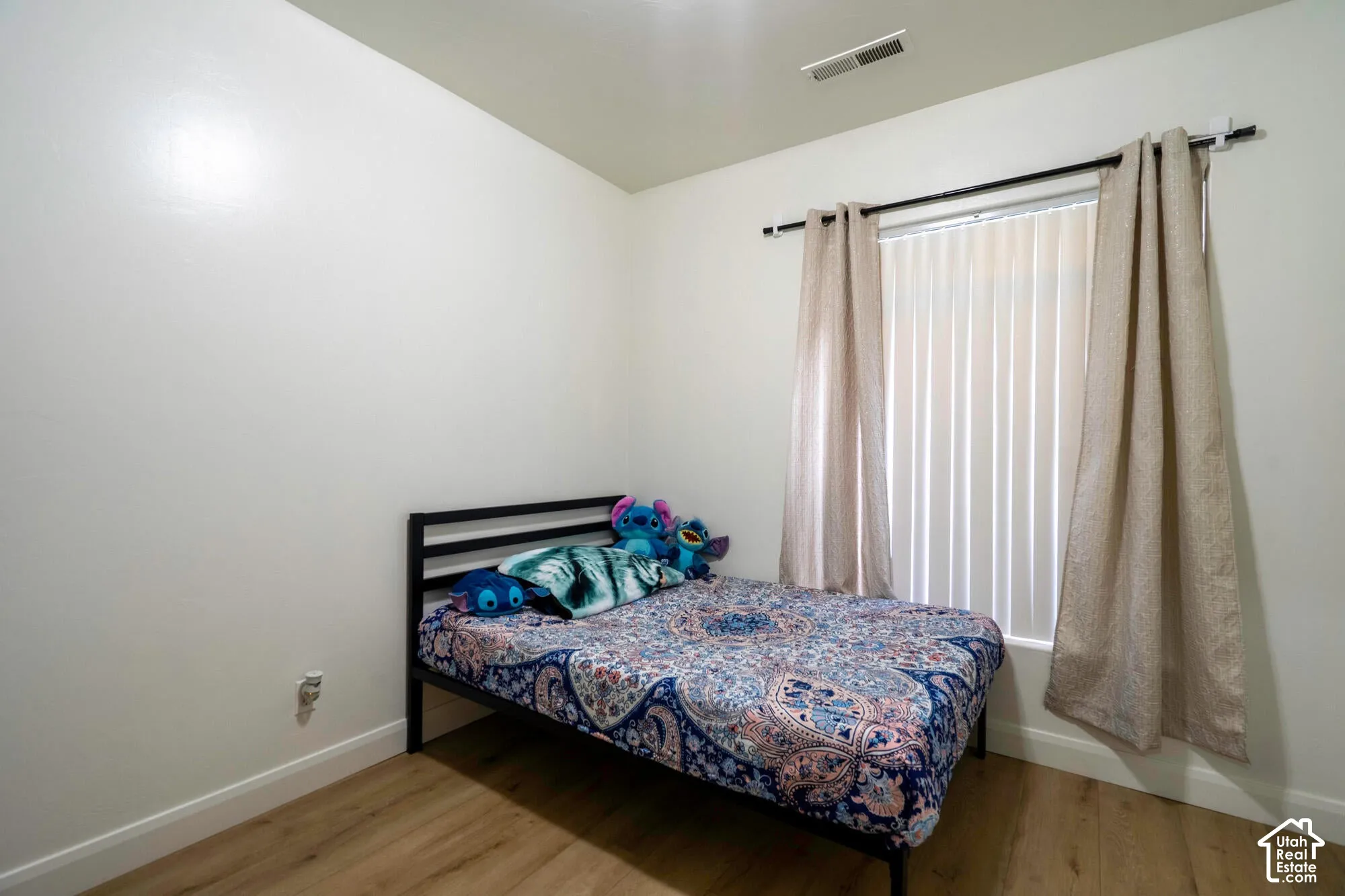 Light-toned wood-finish flooring, white walls, and a window with vertical blinds