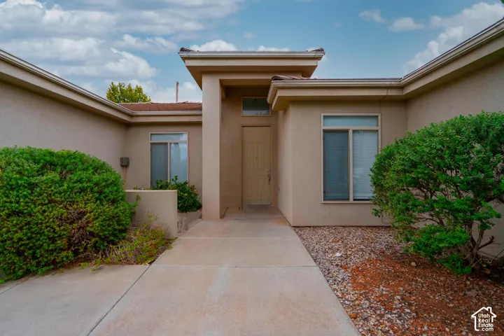Stucco exterior with a covered entry, concrete walkway, and rock landscaping