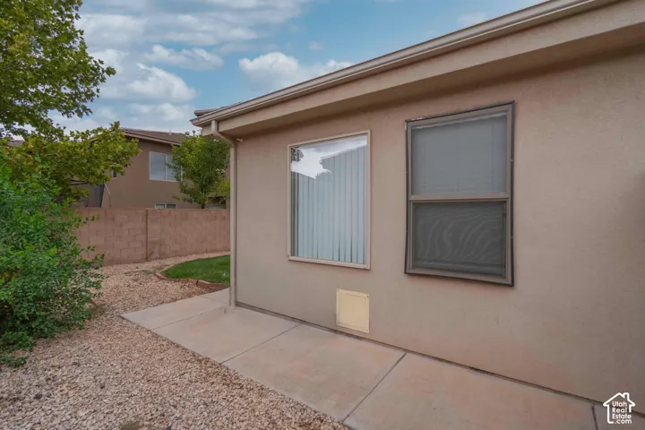 Stucco exterior with a concrete patio, gravel landscaping, and a partial lawn area