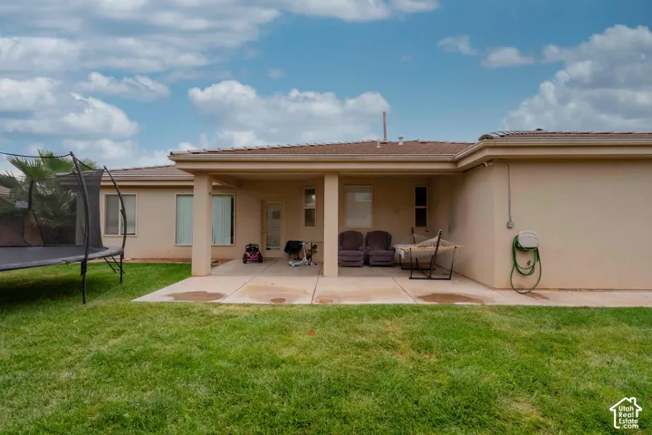 Expansive backyard featuring a manicured lawn, a large covered patio, and stucco exterior walls