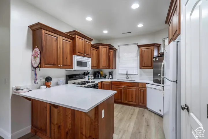 Kitchen featuring wood cabinetry, white countertops, built-in microwave, gas range, and wood-finish flooring