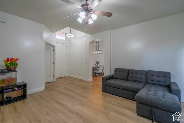 Wood-finish flooring, ceiling fan with integrated lighting, arched doorway, recessed lighting, and a chandelier