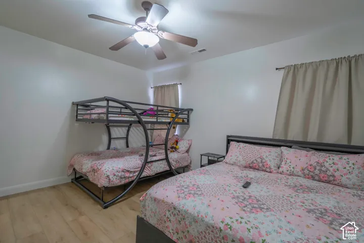 Wood-finish flooring, ceiling fan with integrated lighting, and window treatments