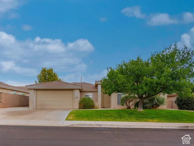 Neutral-toned exterior with an attached garage, paved driveway, and a front lawn