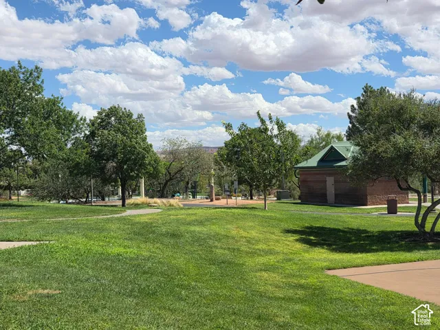 Manicured green lawn with mature trees and a paved pathway