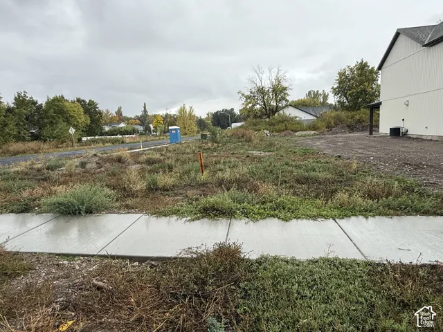 Vacant corner lot featuring a concrete sidewalk and proximity to a paved asphalt road