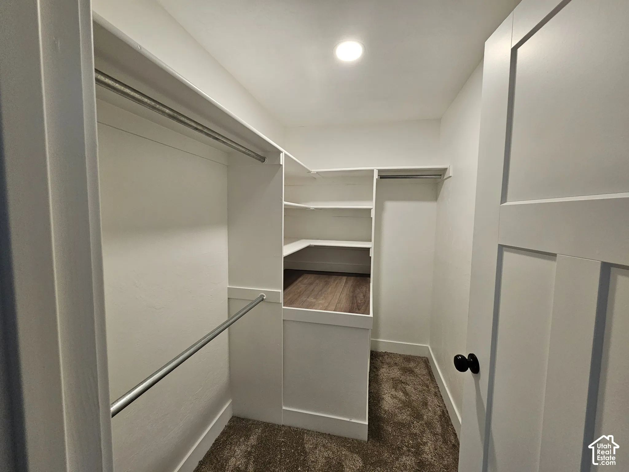 Walk-in closet with integrated shelving, multiple hanging rods, recessed ceiling lighting, and wood-finish flooring in the shelving area