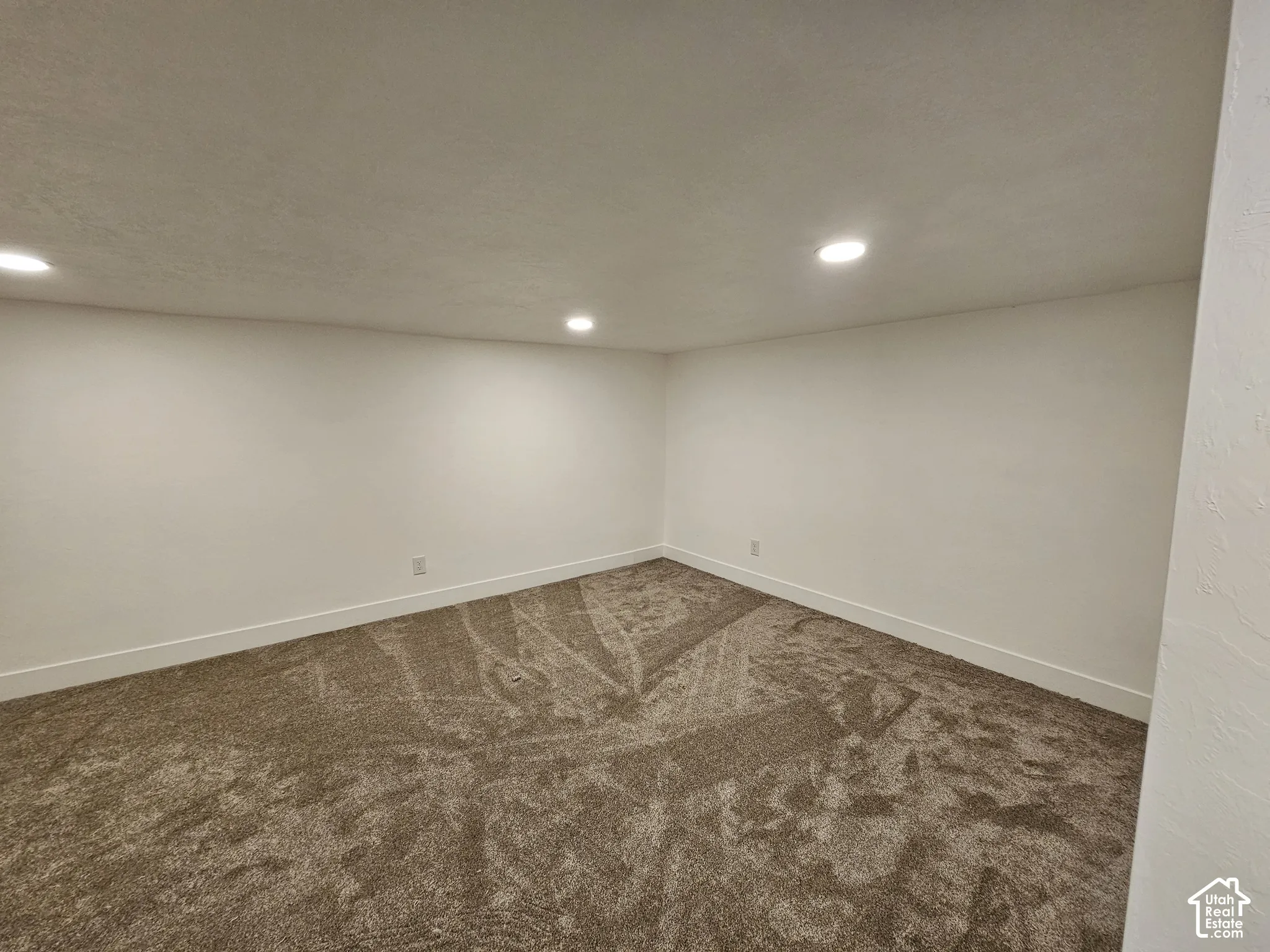 Recessed ceiling lighting illuminates the wall-to-wall carpet and neutral wall finishes