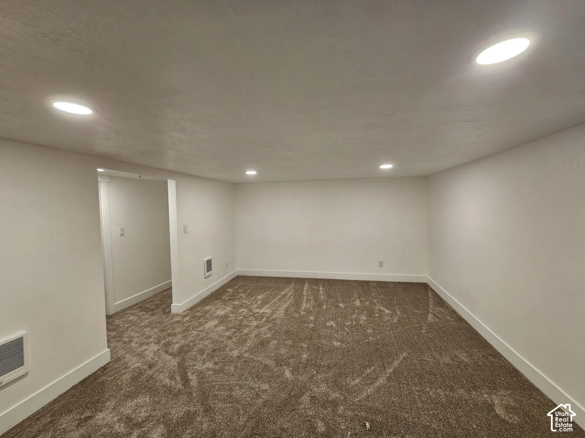 Recessed ceiling lighting, white painted walls, brown patterned carpeting, and white trim