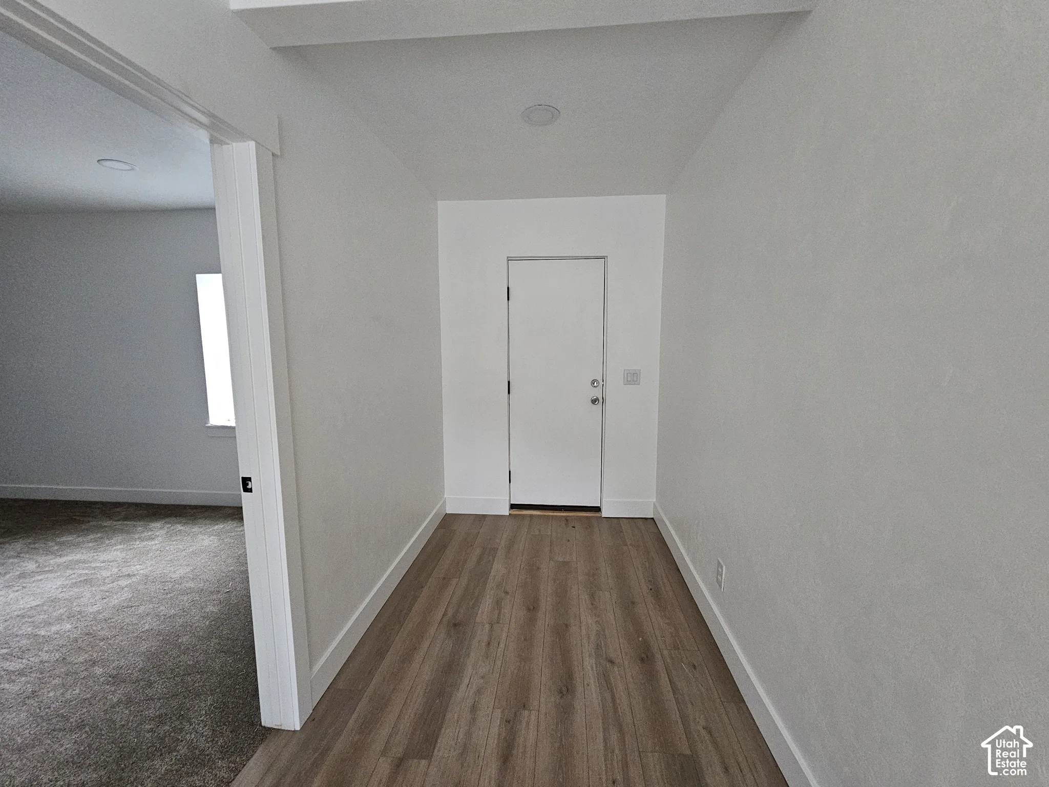 exit to back yard Wood-finish flooring, white door, recessed lighting, white walls, and white trim