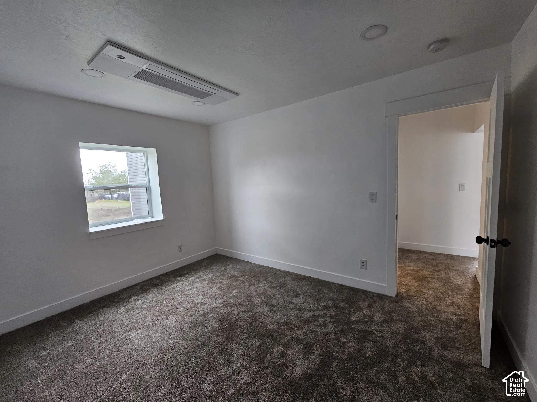 Plush carpeted flooring, a single window, white trim, recessed lighting, and a ceiling-mounted HVAC unit