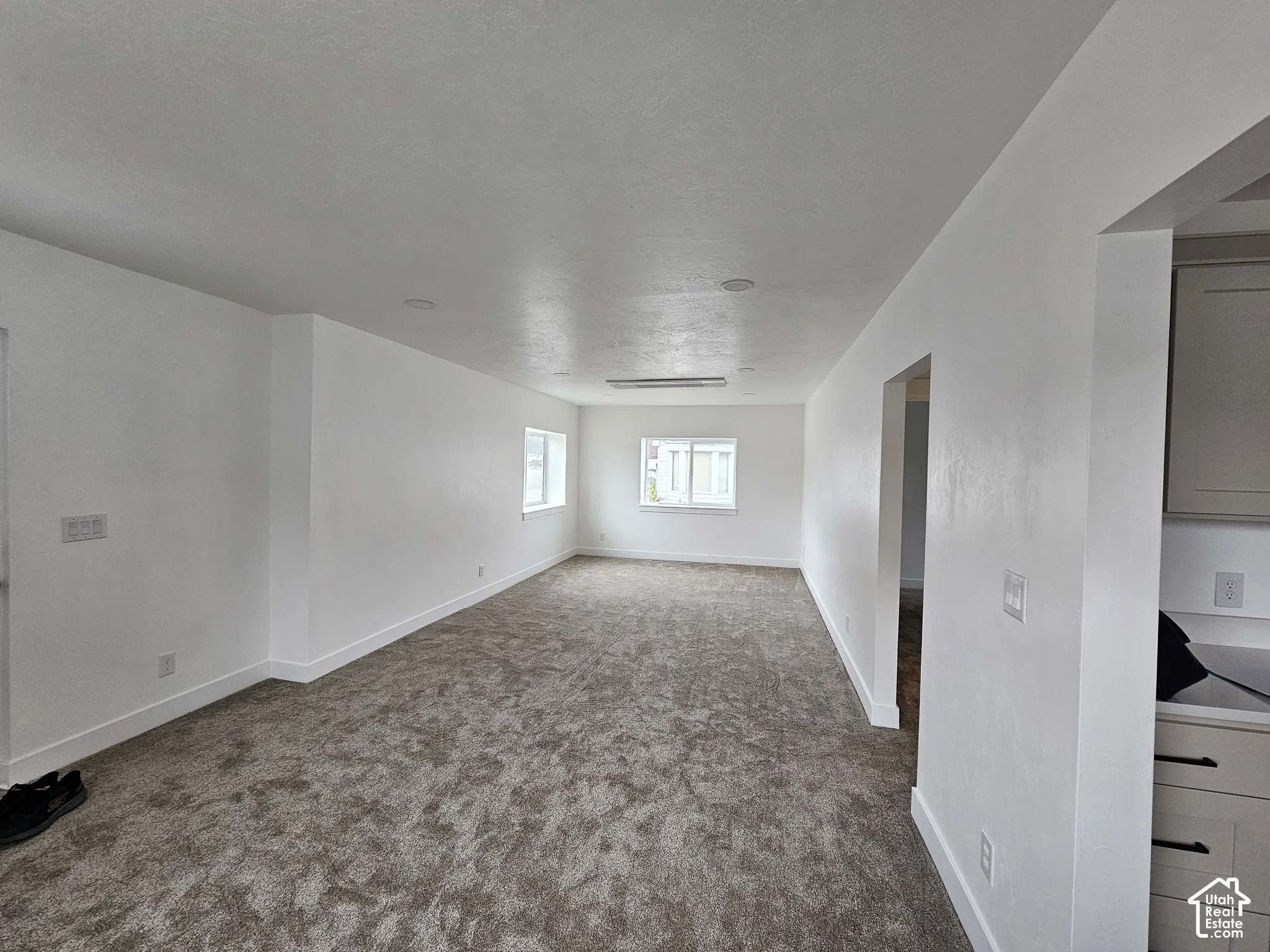 Recessed lighting, wall-mounted light fixture, multiple windows, plush carpet flooring, white cabinetry