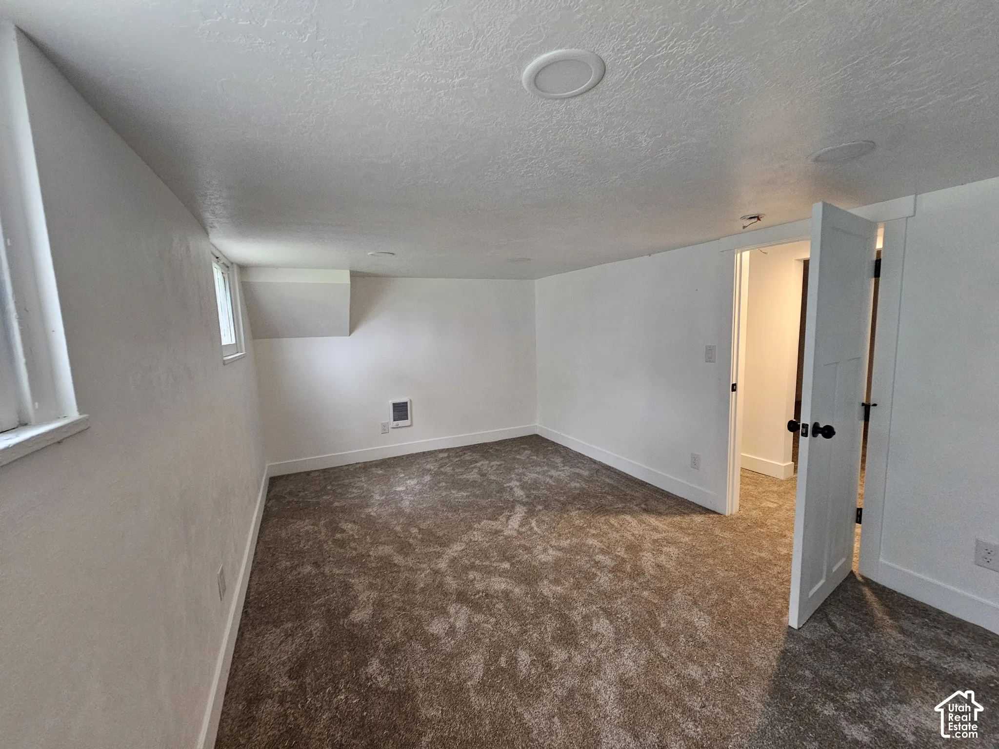 Neutral-toned carpeting, white walls, built-in ceiling lighting, and a white interior door with dark hardware