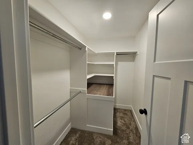 Walk-in closet with integrated shelving, multiple hanging rods, recessed ceiling lighting, and wood-finish flooring in the shelving area
