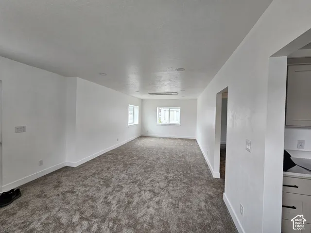 Recessed lighting, wall-mounted light fixture, multiple windows, plush carpet flooring, white cabinetry