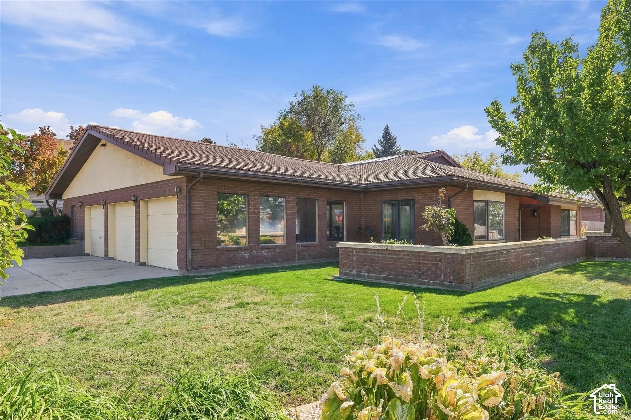 Brick exterior with a multi-car garage, concrete driveway, and tiled roofing