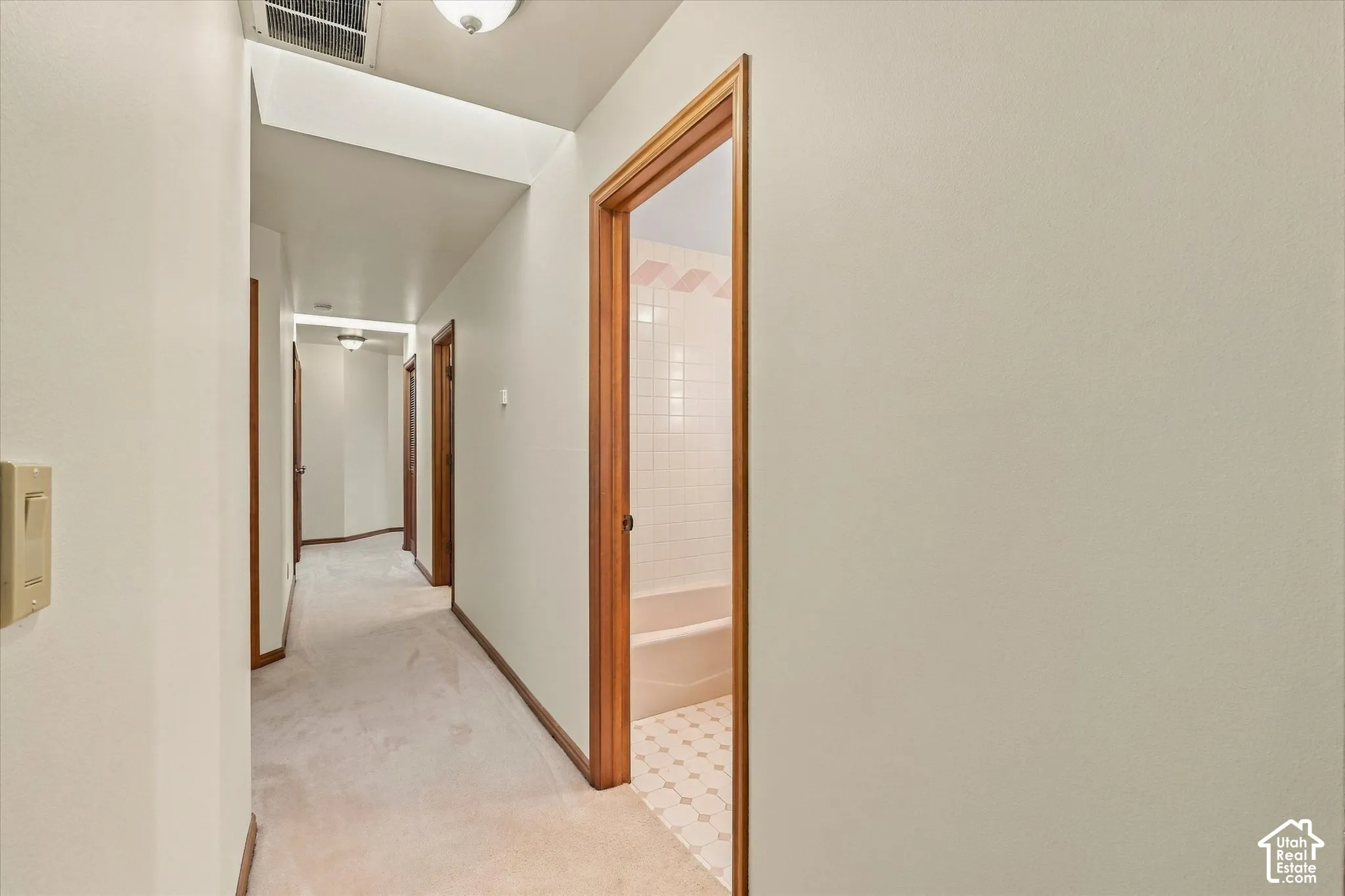 Hallway featuring carpeted flooring and wood trim