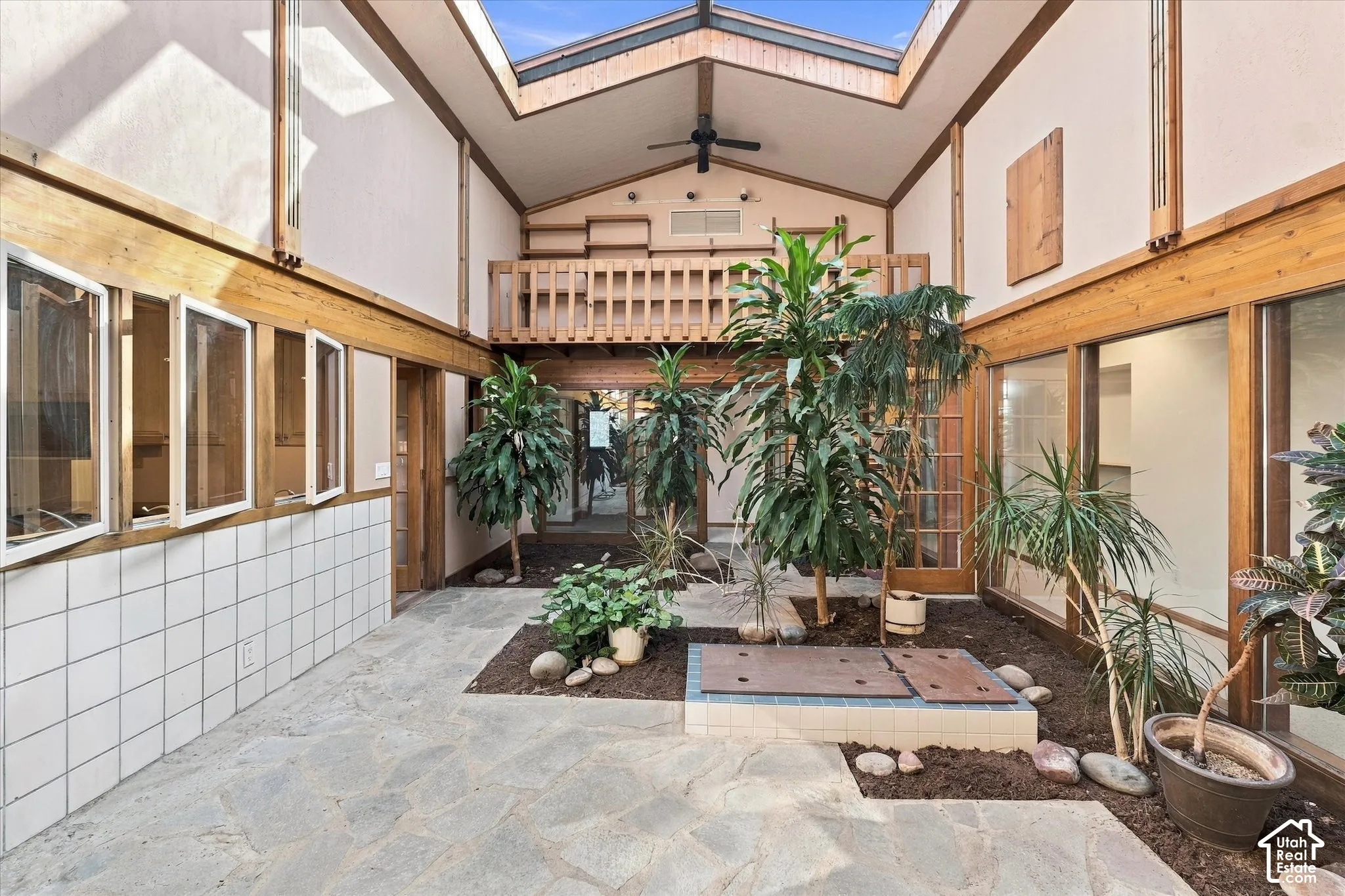 Enclosed conservatory with soaring skylight ceiling, natural stone flooring, and wood-frame glazing
