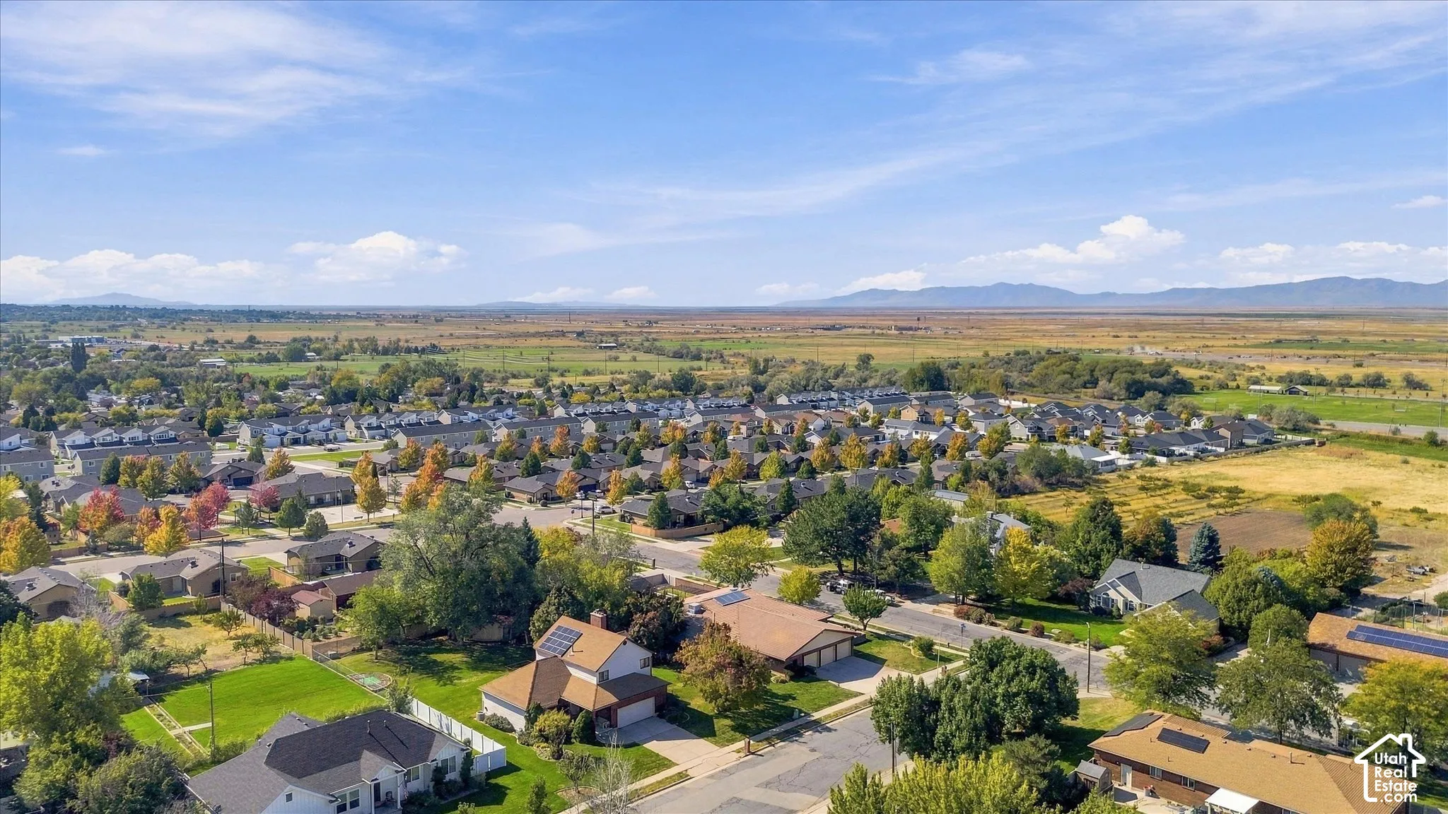 Expansive suburban neighborhood with varied housing styles, mature trees, and mountainous background