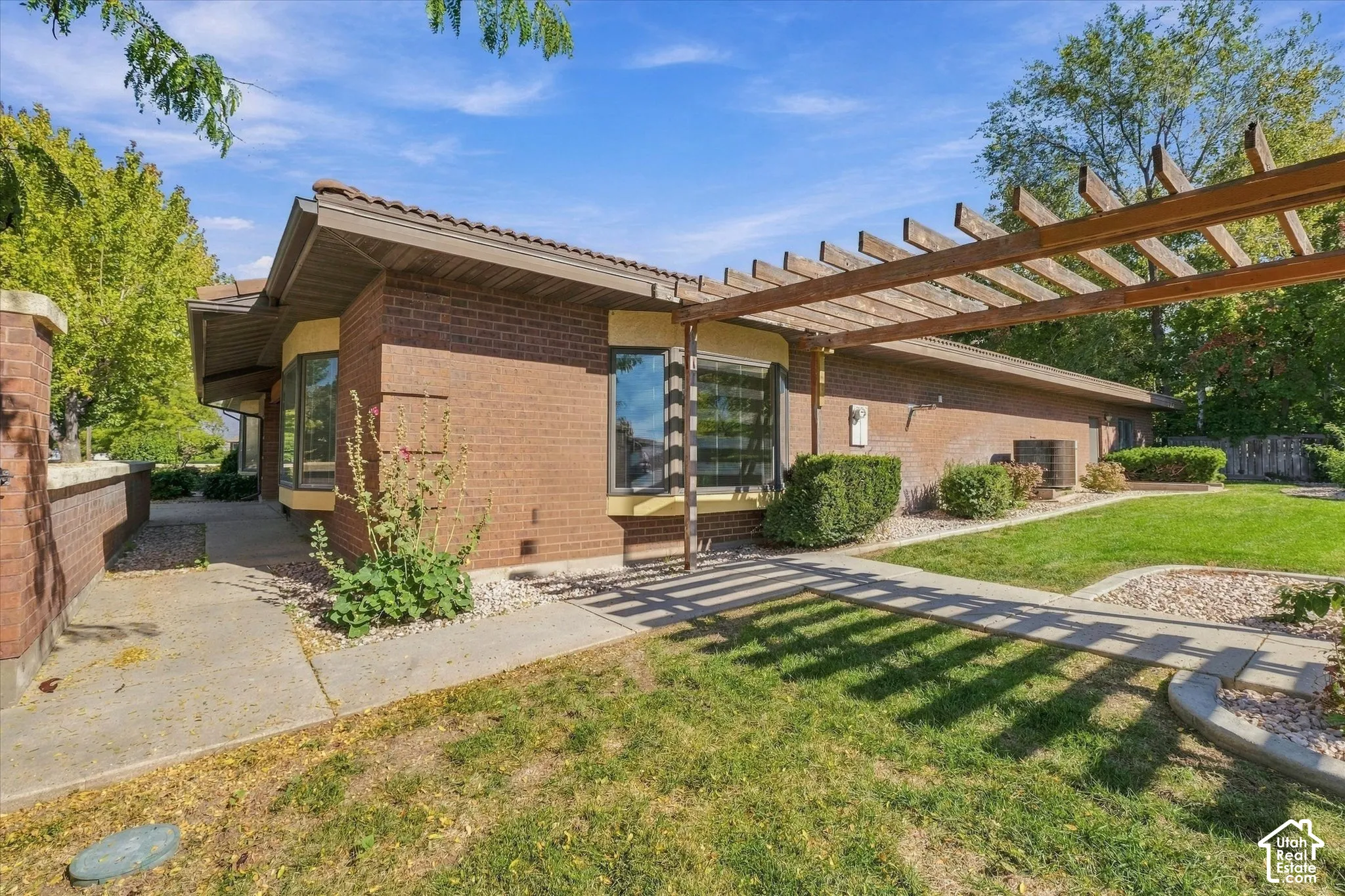 Brick exterior with a tile roof, featuring a wood pergola and bay windows