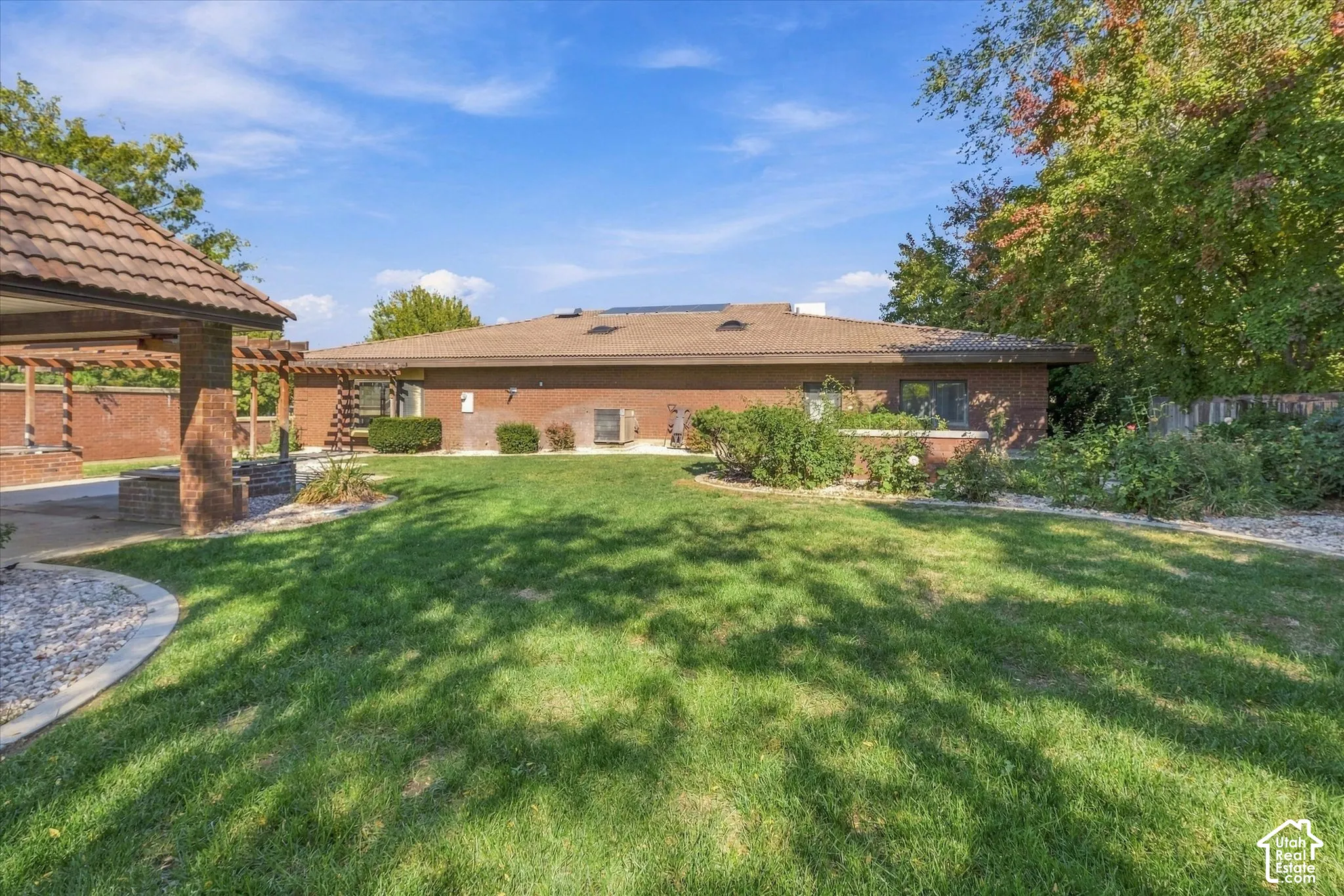 Expansive backyard featuring a brick exterior and a covered patio with a tile roof