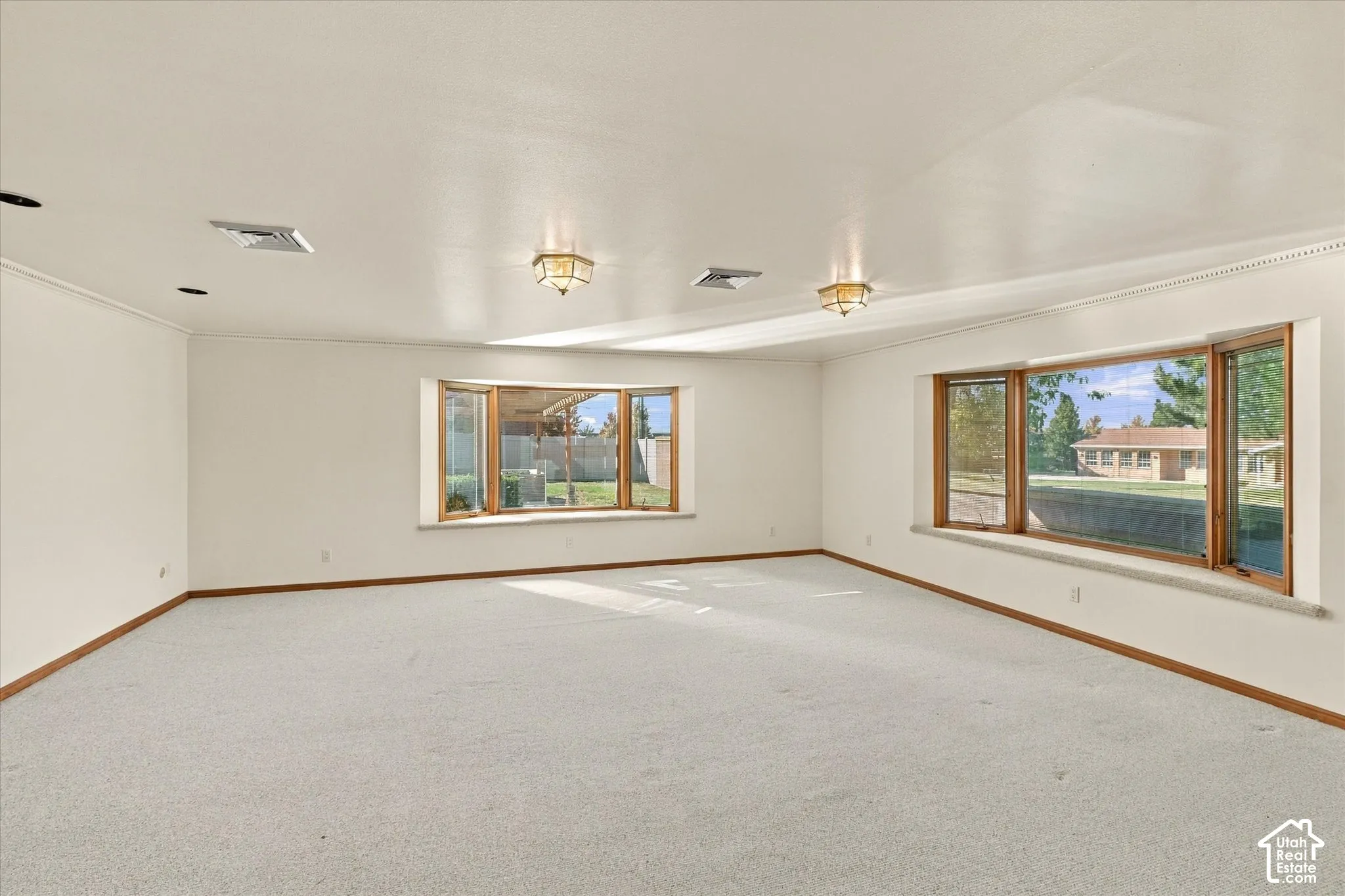 Spacious room featuring light-colored carpeting and white walls