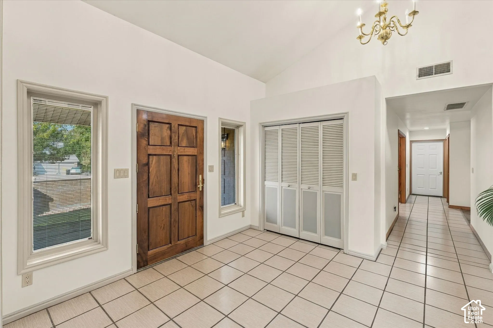 Vaulted entry featuring a wood panel front door, tile flooring, and integrated lighting
