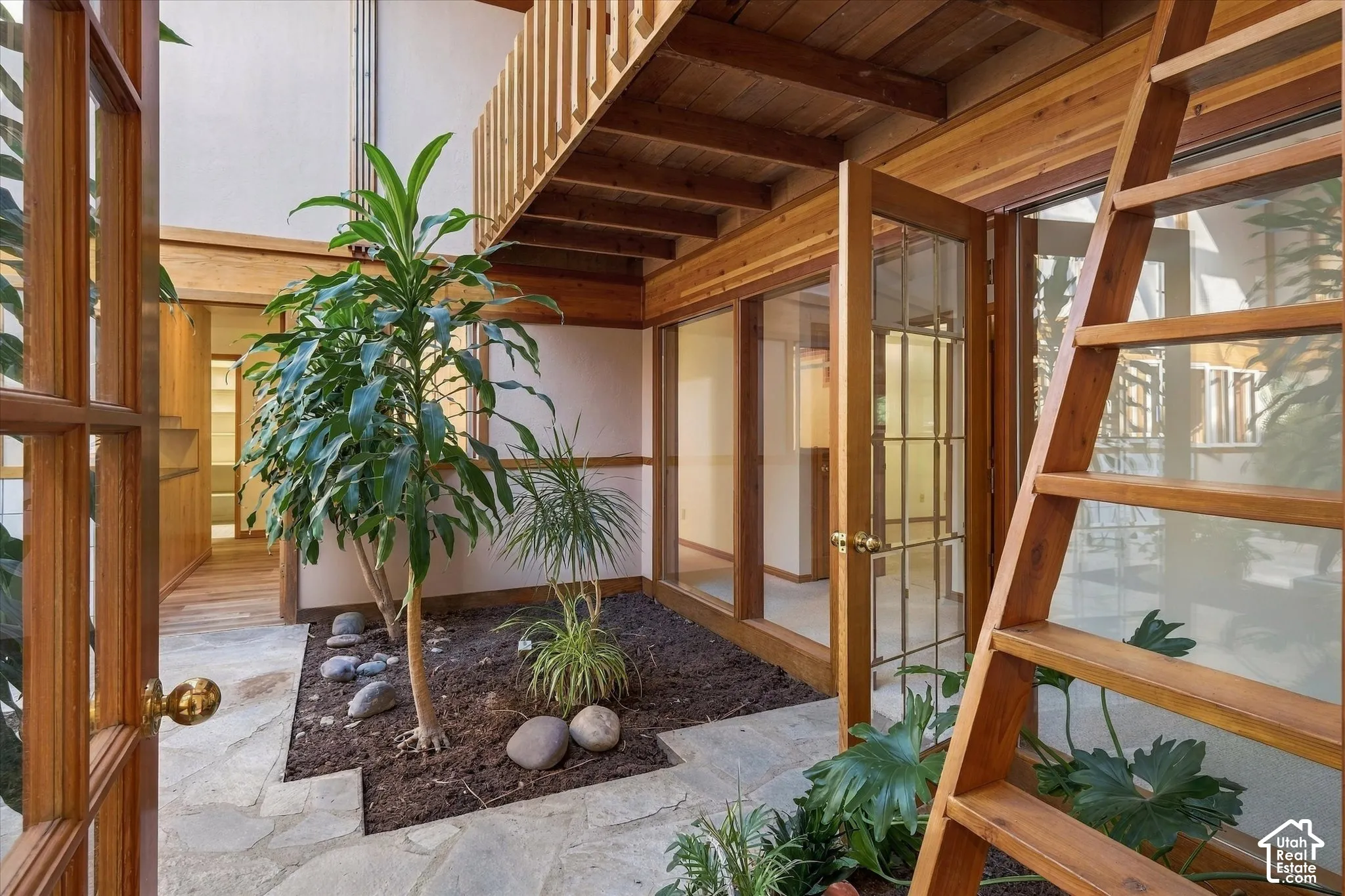 Central courtyard featuring natural stone paving, mature plantings, and a wooden overhead walkway