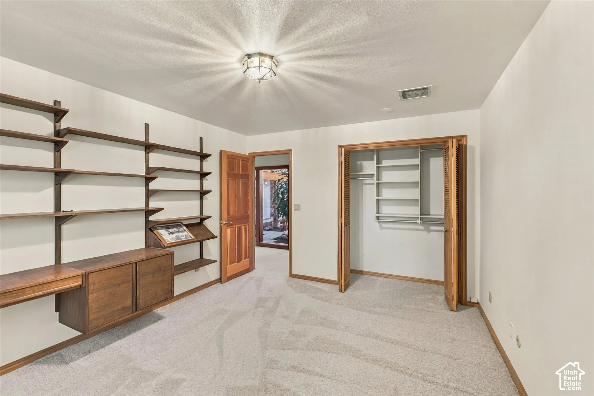 Built-in shelving with integrated desk, recessed lighting, carpet flooring, bi-fold closet doors, and wood-finish interior doors
