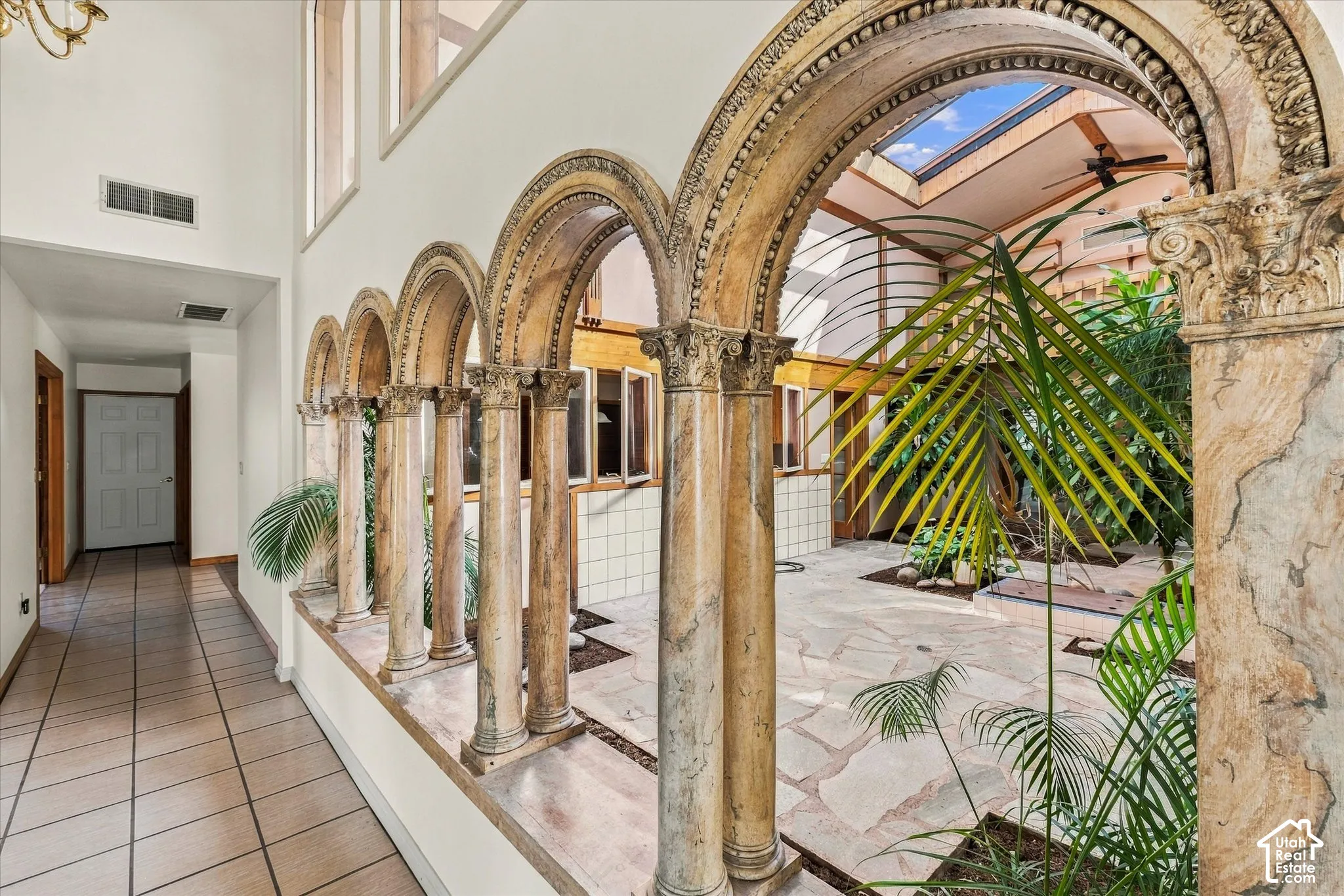 Architectural arched stone columns, stone tile flooring, interior skylight, and high ceilings