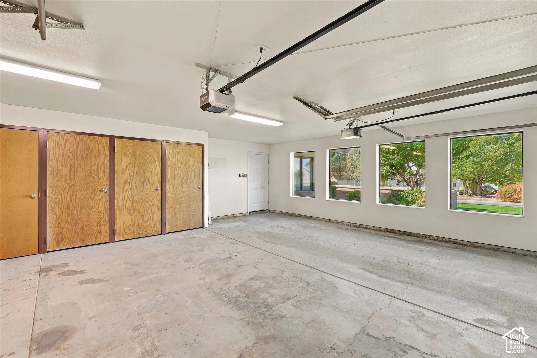 Attached garage featuring a concrete floor, four panel windows, a white door, and multiple storage closets with wood-finish doors