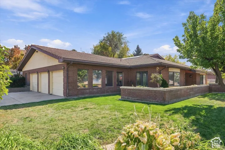 Brick exterior with a multi-car garage, concrete driveway, and tiled roof