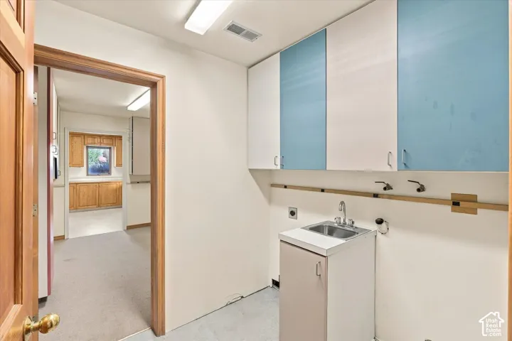 Laundry with both gas and electric hookups, wall-mounted cabinetry, utility sink with a cabinet base and extra power outlets.