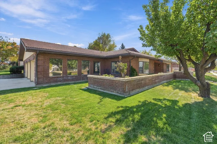 Brick exterior with a tiled roof, mature landscaping, and a three-car garage
