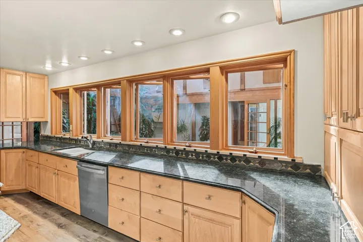 Kitchen with light wood cabinetry, recessed lighting, ample countertop, and a row of casement windows to observe the atrium