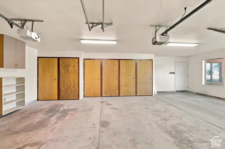 Spacious garage featuring multiple storage closets, overhead lighting, and natural light.