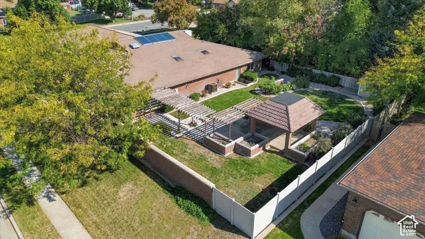 Expansive rear yard featuring a tiled-roof gazebo, pergola, mature trees, and a brick privacy wall