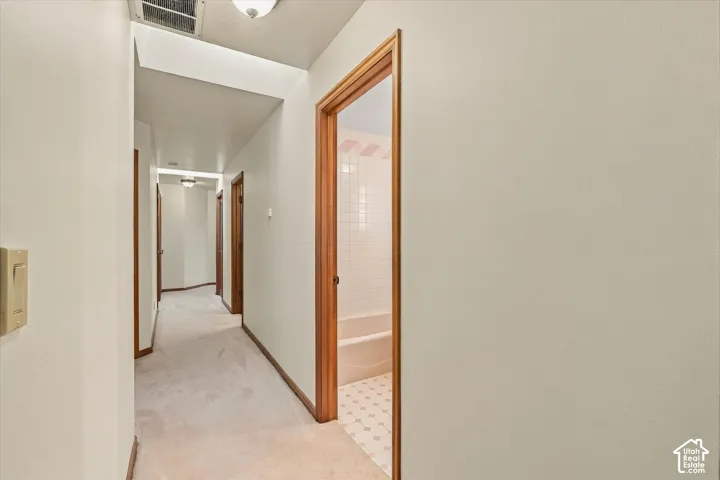 Hallway featuring carpeted flooring and wood trim