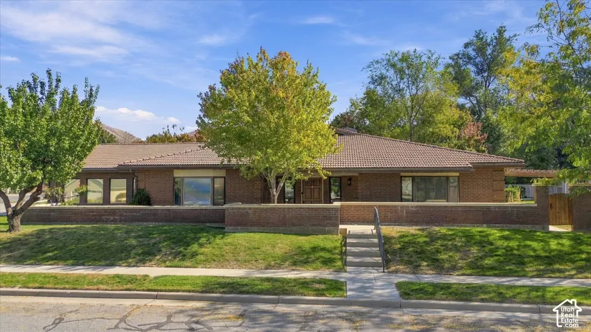 Single-story brick exterior with a tile roof, established landscaping, and a concrete walkway