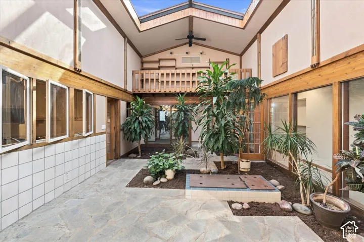 Enclosed conservatory with soaring skylight ceiling, natural stone flooring, and wood-frame glazing