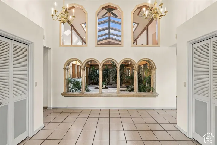 Tile flooring throughout, arched window features, high ceilings, and two brass chandeliers